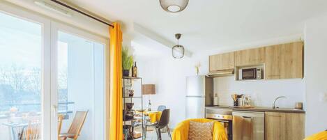 A modern apartment with a dining area, kitchen, and a balcony with outdoor seating.