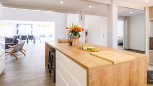 Een moderne keuken met een houten aanrecht, een eethoek met stoelen en uitzicht op buiten.