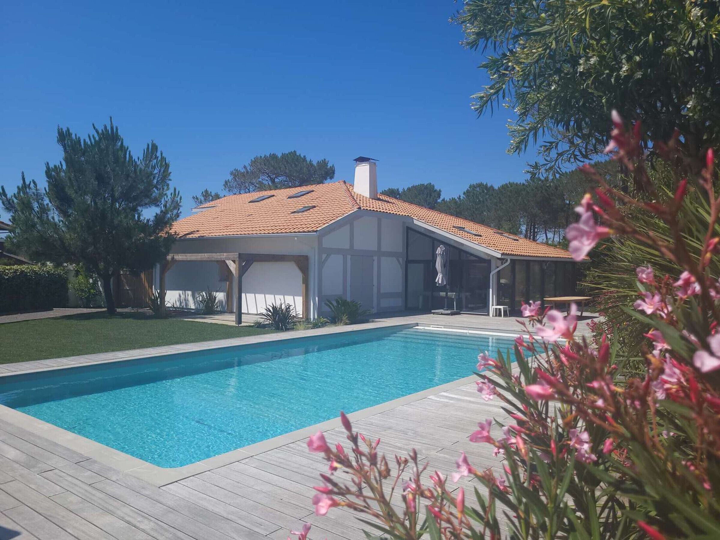 A modern house with a swimming pool, a covered patio, and a garden.