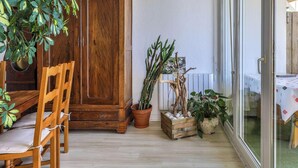 A wooden dining table with chairs, a cabinet, and potted plants.