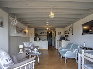 Ein Wohnzimmer mit einer Couch, Sesseln, einem kleinen Tisch und einem Fernseher.