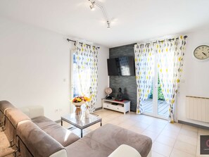 Ein modernes Wohnzimmer mit einer Couch, einem Couchtisch mit Blumenvase, einem Fernseher und einer Buddha-Statue.