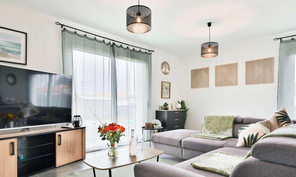 A modern living room with a television, sofa, and decorative wall art.