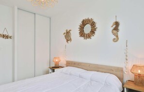 A bedroom with a bed, wooden headboard, wall-mounted decor, and bedside lamps.