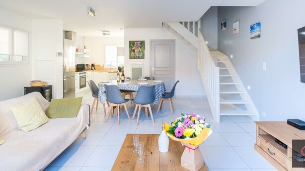 Eine moderne Wohnung mit Essbereich, Küche, Wohnzimmer und Treppe.