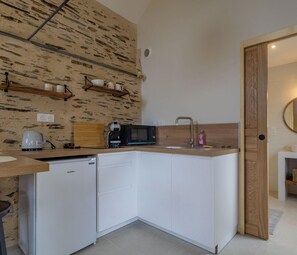 A compact kitchen with white cabinets, a microwave, a coffee maker, and a wooden countertop. - Studio with AC, peaceful village (Chenillé-Champteussé)