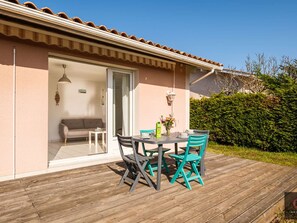 A patio with a table and chairs, a sofa, and a sliding glass door leading to an interior space. - House near lake - 5 guests (Biscarrosse)