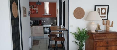 A modern kitchen with a dining area, a wooden dresser, and a potted plant.