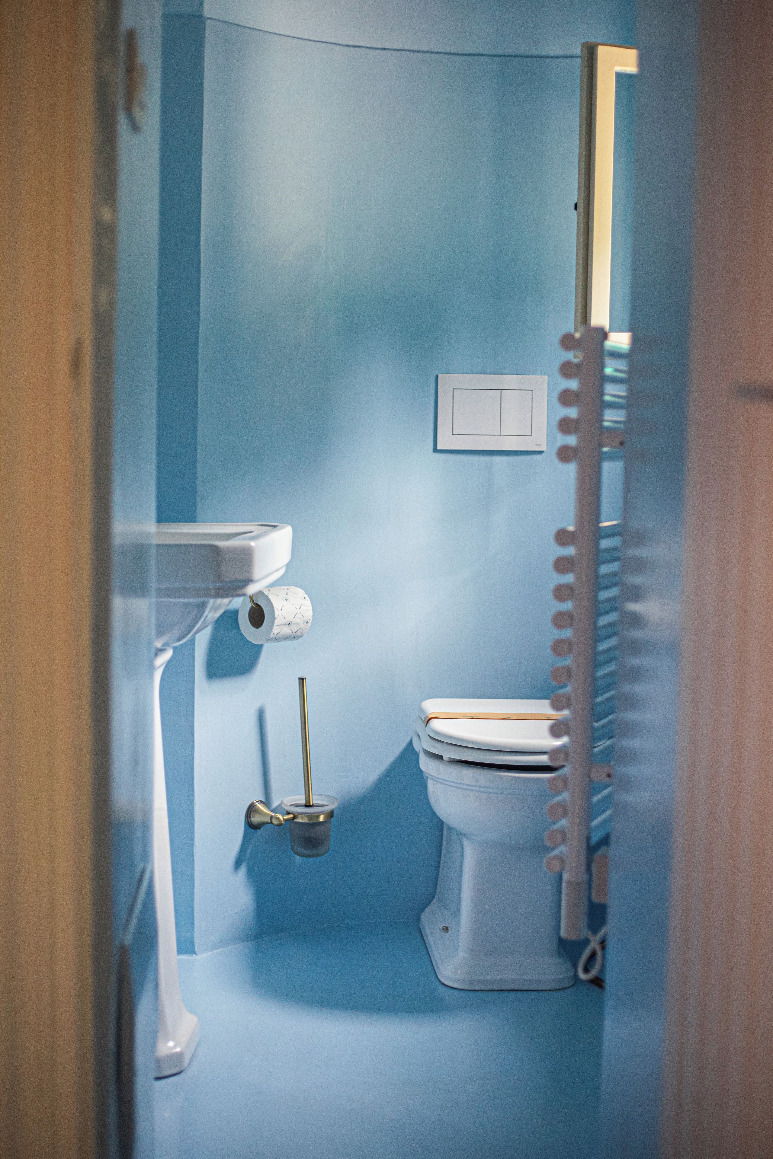 A bathroom with a toilet, a roll of toilet paper, and a hand dryer.