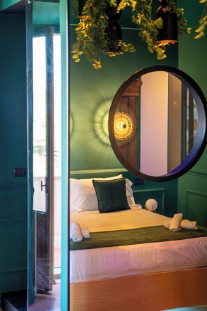 Una stanza con un letto, uno specchio tondo e una finestra.