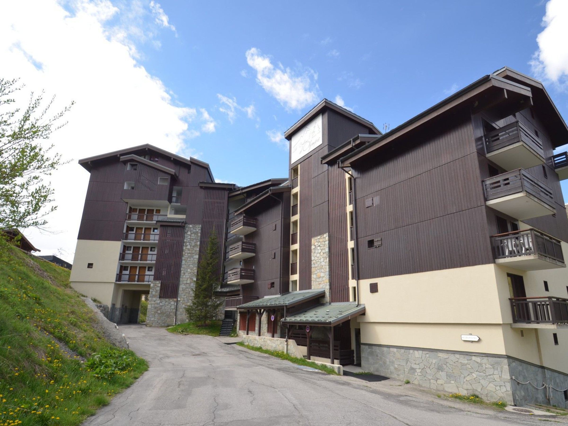 A multi-story hotel with balconies, a stone facade, and a paved driveway leading to the entrance.