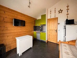 Eine kompakte Küche mit Einbauofen, Mikrowelle und Kaffeemaschine.