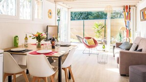 A dining area with a table set for four, chairs, a vase with flowers, and a bottle of wine. - Charming house in Navarrosse - 6 guests (Biscarrosse)