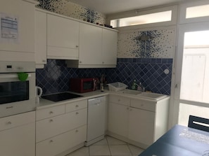 A compact kitchen with white cabinets, a microwave, a sink, and a dishwasher. - Charming apartment in Biscarrosse city center (Biscarrosse)