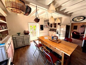 Eine Küche mit Holzschränken, einer zentralen Kochinsel, hängenden Körben und einem Kühlschrank.