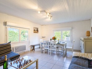 Ein Zimmer mit Schachbrett, einem Esstisch mit Stühlen, einer Couch und einem Schrank.