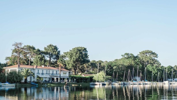 Una propiedad frente al lago con una casa grande, un muelle y barcos, y un lago tranquilo.