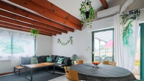 Una habitación acogedora con techo de madera, una mesa redonda y un sofá con cojines.