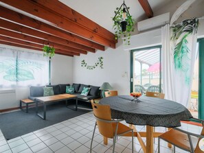 Ein gemütliches Zimmer mit Holzbalkendecke, einem runden Tisch und einer Couch mit Kissen.