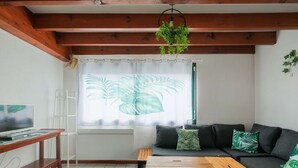 Una sala de estar con un sofá, una mesa de centro, un televisor y una ventana con cortinas.