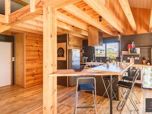 A wooden interior with a kitchen area, a dining table with chairs, and a visible door. - Chalet with jacuzzi and pétanque - 6 guests (Gastes)