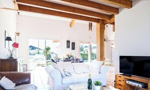 Ein großzügiges Wohnzimmer mit einem weißen Sofa, einem Fernseher und einer Holz-Unterhaltungsecke.