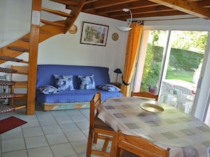 Ein Zimmer mit einem blauen Sofa, einem Holzesstisch und einer Treppe.