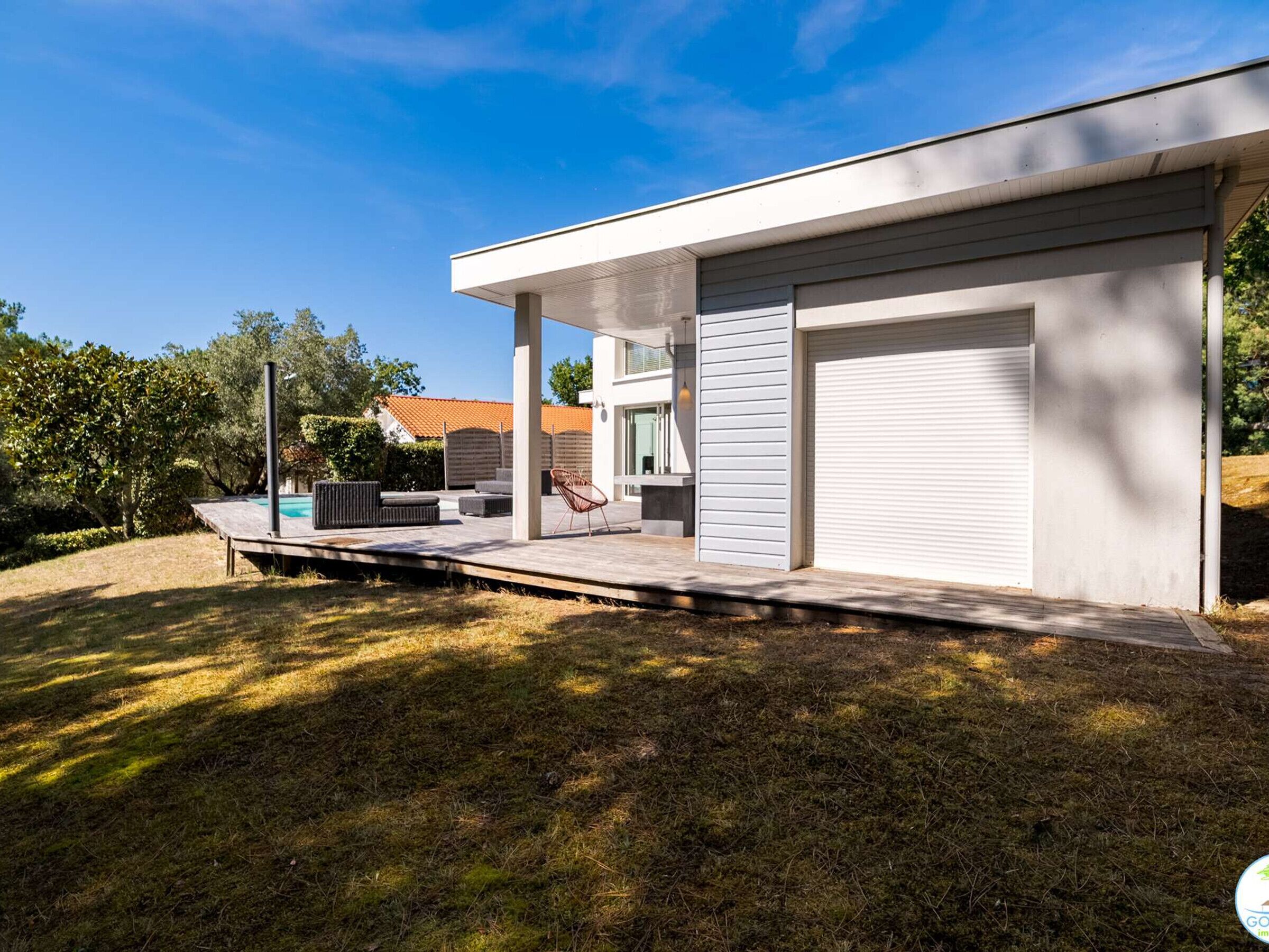 Een modern huis met een overdekte patio, een garage en een zwembad.