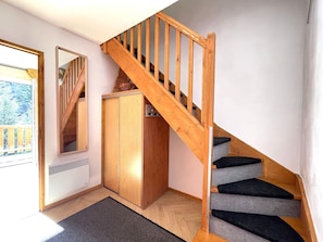 Eine Holztreppe mit Handlauf, ein Holzschrank und ein Spiegel an der Wand.