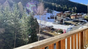A snowy mountain village with wooden buildings, a clear sky, and a rainbow. - Comfortable duplex, slope view - 6 guests (Valfréjus)