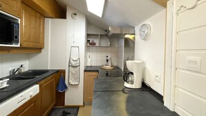 A compact kitchen with wooden cabinets, a microwave, a coffee maker, and a clock on the wall. - Comfortable duplex, slope view - 6 guests (Valfréjus)