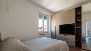 Ein Schlafzimmer mit einem Bett, einem Fernseher, einem Kleiderschrank und einem Fenster.
