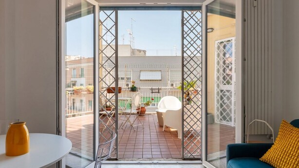 Ein modernes Zimmer mit einer Schiebeglastür, die zu einer Terrassenanlage im Freien führt.
