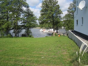 A grassy area with a lake, boats, and a building with a satellite dish. - After stand UP paddling, barbecue on the terrace and enjoy the sunsets (Klein Köris)