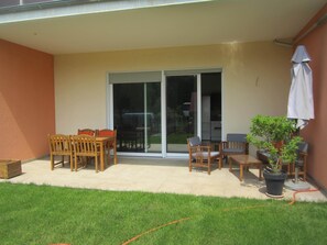 A patio with a table and chairs, a sliding glass door, and a potted plant. - After stand UP paddling, barbecue on the terrace and enjoy the sunsets (Klein Köris)