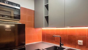 A modern kitchen with a Hisense refrigerator, a stainless steel sink, and a black stovetop. - Casa Castoro - Nel cuore della Val di Peio (Peio Fonti)