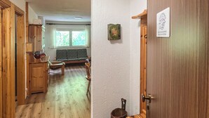 A hallway with wooden flooring, a wooden door, a bench, and a window with a view of greenery. - Casa Castoro - Nel cuore della Val di Peio (Peio Fonti)