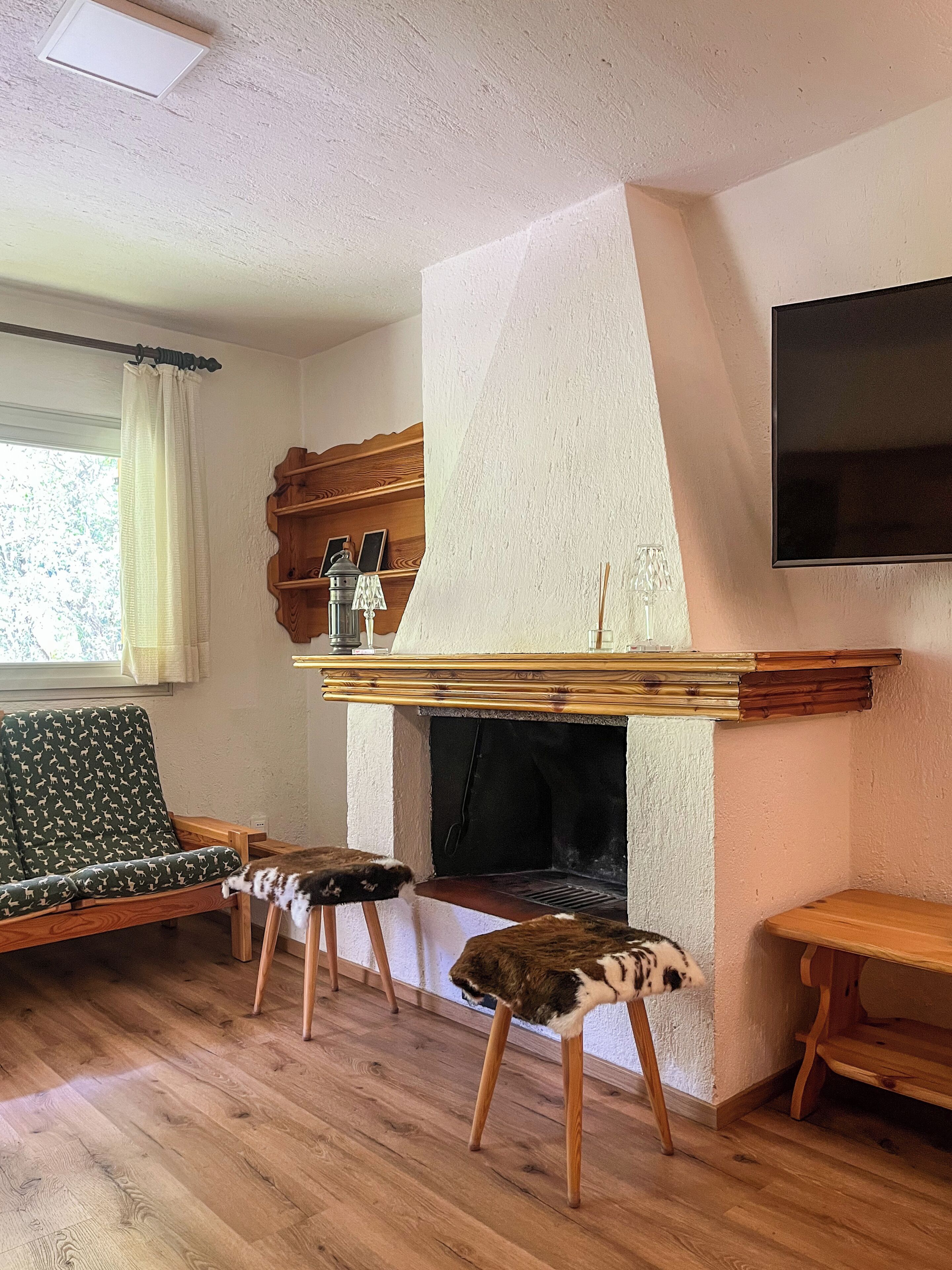 Un salon avec une cheminée, un canapé, un banc en bois et un téléviseur fixé au mur.