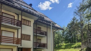 A two-story building with a balcony, a stone pathway, and a grassy area. - Casa Castoro - Nel cuore della Val di Peio (Peio Fonti)
