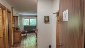 A hallway with wooden flooring, a bench, and a door with a sign. - Casa Castoro - Nel cuore della Val di Peio (Peio Fonti)