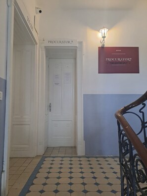 Ein Korridor mit Fliesenboden, einer weißen Tür mit der Aufschrift 'PROCURATOR7' und einem an der Wand befestigten Schild, auf dem 'PROCURATOR7 THAI CENTAR SPLIT' steht.