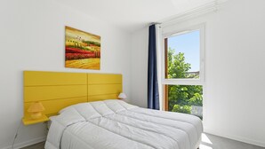A bedroom with a bed, a painting, a window with curtains, and a lamp. - Renovated flat near the town centre & swimming pool (Grasse)