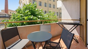 A balcony with a table and chairs, a view of a building with a chimney, and a tree. - Renovated flat near the town centre & swimming pool (Grasse)