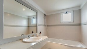 A bathroom with a sink, mirror, and bathtub. - Sun Flower Apartment (Santa Cruz)
