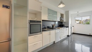 A modern kitchen with white cabinetry, a built-in oven, and a large window offering a view of the outside. - Sun Flower Apartment (Santa Cruz)