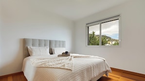 A bedroom with a bed, a window, and a view of a hill. - Sun Flower Apartment (Santa Cruz)