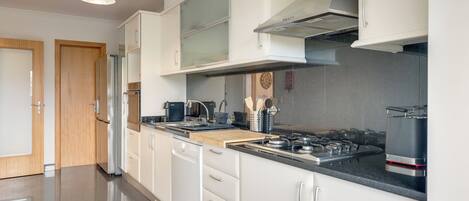 A modern kitchen with white cabinetry, a black countertop, and stainless steel appliances.