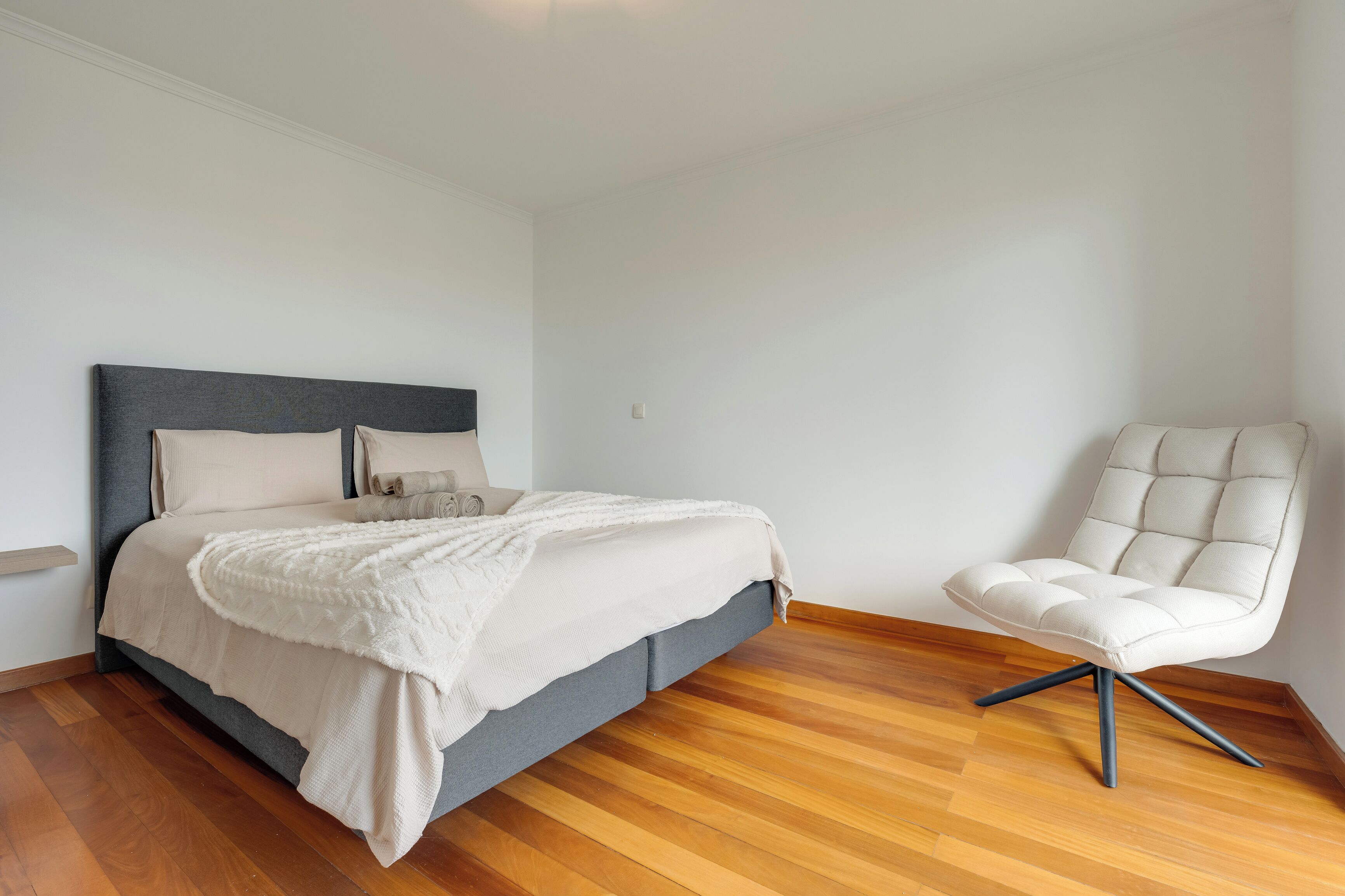 Ein Schlafzimmer mit einem Bett, einem Sessel und Holzboden.