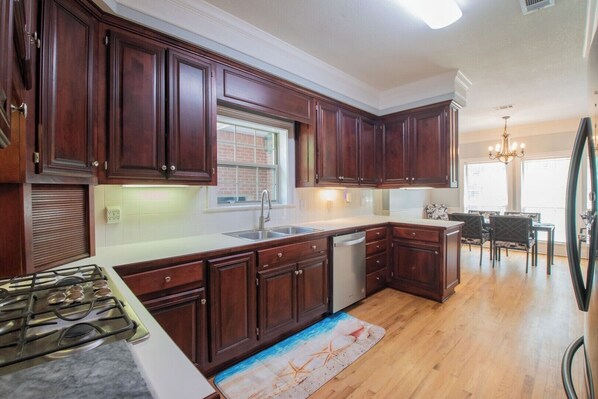 A kitchen with dark wood cabinets, a stainless steel sink, a dishwasher, and a gas stove.