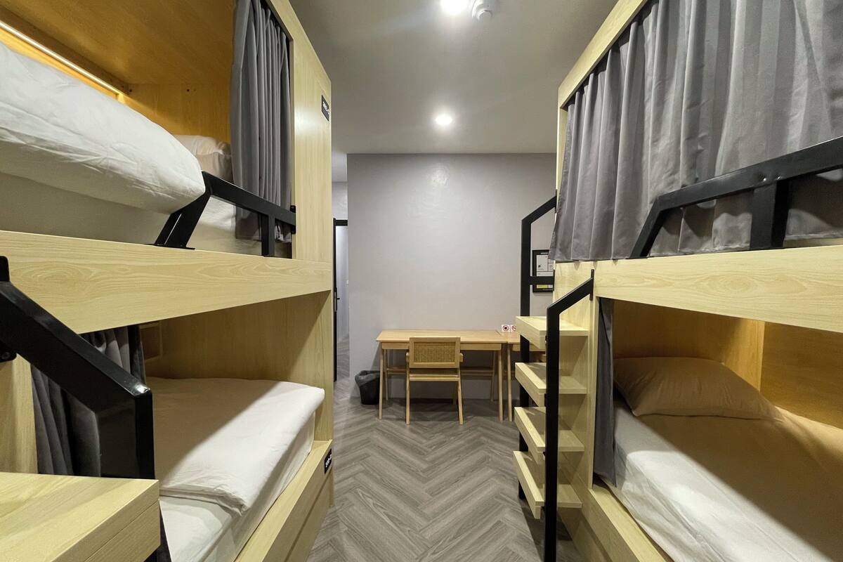 A room with bunk beds, a desk, and a chair.